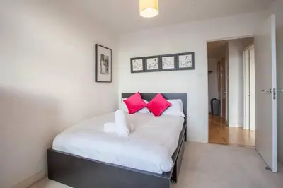 a bedroom with a white bed with red pillows at Apartment with river view next to hydro in Glasgow