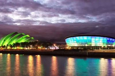 a building with green and blue lights on the water at Apartment with river view next to hydro in Glasgow