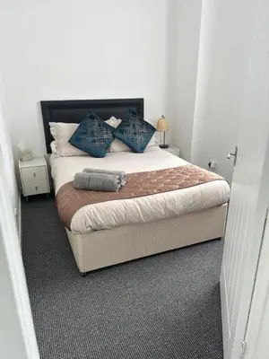 a bedroom with a large bed with blue pillows at Hillhead Apartment in Coylton