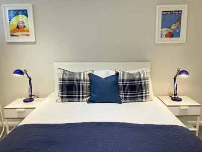 a bed with blue and white pillows and two lamps at Park Mews Glasgow in Glasgow