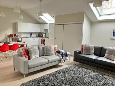 a living room with two couches and a kitchen at Park Mews Glasgow in Glasgow