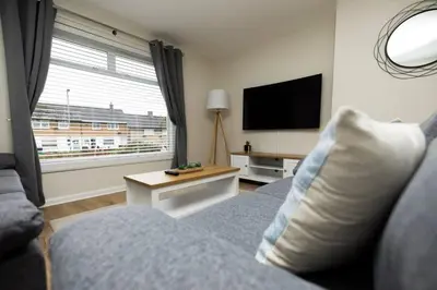 a living room with a couch and a flat screen tv at Pristine 3 bedroom house in East Kilbride
