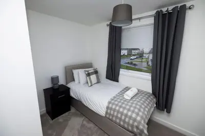 a small bedroom with a bed and a window at Pristine 3 bedroom house in East Kilbride