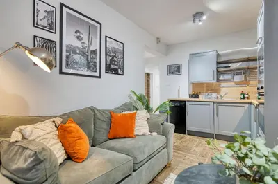 a living room with a couch and a kitchen at Spacious 4 Bedroom Apt Near West End Glasgow in Glasgow