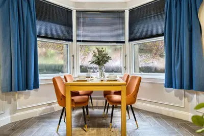 a dining room with blue curtains and a yellow table and chairs at Spacious 4 Bedroom Apt Near West End Glasgow in Glasgow