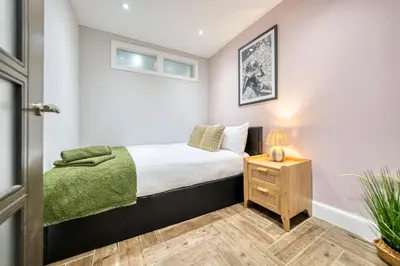 a small bedroom with a bed and a night stand at Spacious 4 Bedroom Apt Near West End Glasgow in Glasgow