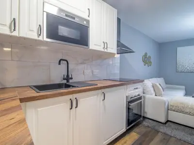 a kitchen with white cabinets and a sink and a couch at Happy Haven Home, West End - Pass the Keys in Glasgow