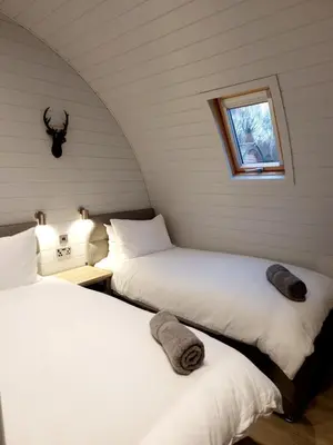 two beds in a room with a window at The Ness, Lodge with Hot Tub in Crieff