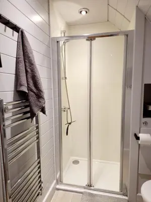 a shower with a glass door in a bathroom at The Ness, Lodge with Hot Tub in Crieff