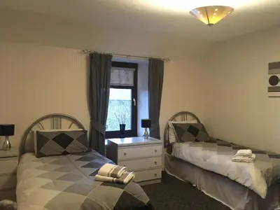 a bedroom with two beds and a window at Farmhouse in Clydebank