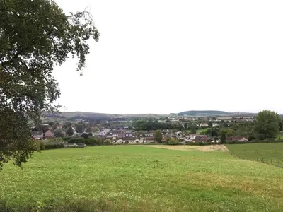 a field of green grass with a town in the distance at Farmhouse in Clydebank