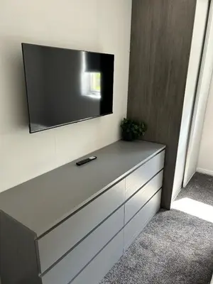 a flat screen tv on a wall with a dresser at Spacious 2 bedroom apartment, entire place in Greenock