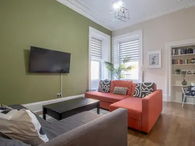 a living room with two couches and a flat screen tv at City Haven Main Door & Parking - Pass the Keys in Glasgow