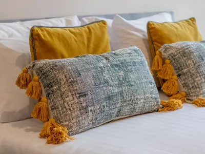 a bed with two pillows with orange tassels at City Haven Main Door & Parking - Pass the Keys in Glasgow