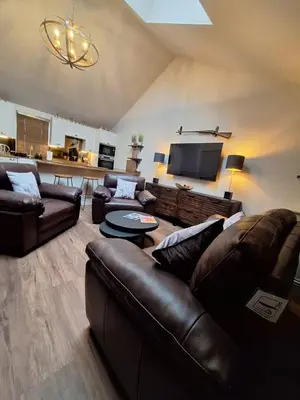 a living room with leather couches and a flat screen tv at Luxurious Cottage Machrihanish in Drumlemble