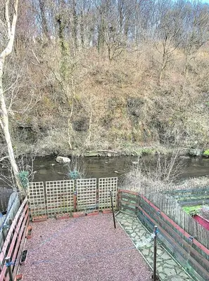 a fence next to a river with a bridge at Cosy 2 bed home Glasgow South in Cathcart