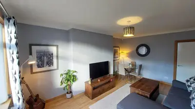 a living room with a couch and a flat screen tv at Cosy 2 bed home Glasgow South in Cathcart