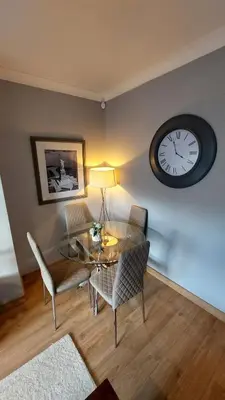 a dining room with a glass table and a clock at Cosy 2 bed home Glasgow South in Cathcart