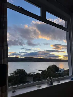 a window with a view of a body of water at Greenwood South - Luxury beachfront home with log burner in Kames