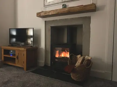 a living room with a fireplace and a television at Greenwood South - Luxury beachfront home with log burner in Kames