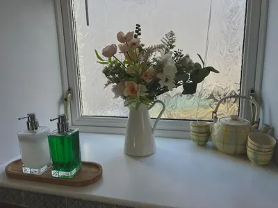 a vase filled with flowers sitting on a window sill at Greenwood South - Luxury beachfront home with log burner in Kames