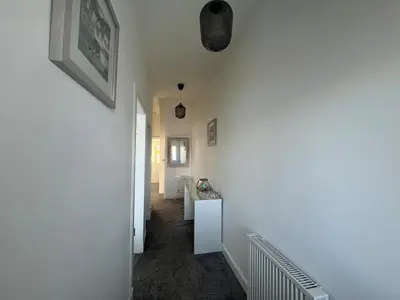 a hallway with a white wall and a white sink at Greenwood South - Luxury beachfront home with log burner in Kames