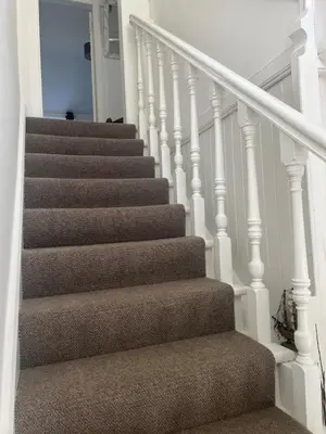 a staircase with brown carpet and white railings at Greenwood South - Luxury beachfront home with log burner in Kames