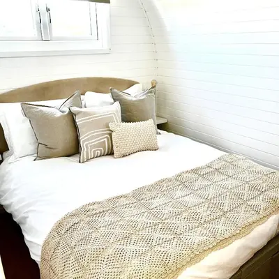 a bed with white sheets and pillows in a room at Heather Pod in Perth
