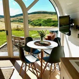 a room with a table and chairs and a large window at Heather Pod in Perth