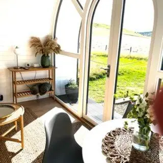 a living room with a large window with a cat at Heather Pod in Perth
