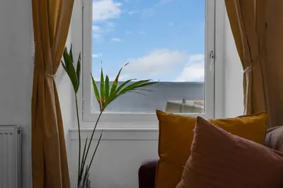 a window with a view of the ocean and a plant at Free Parking - City Centre - Stunning Views - Great Location in Edinburgh