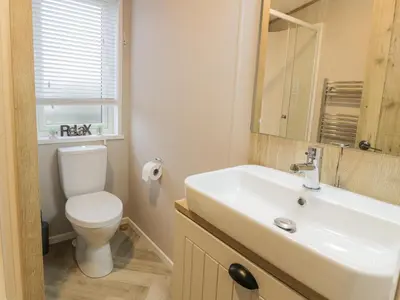 a bathroom with a sink and a toilet and a mirror at Debonair Lodge in Newton Stewart