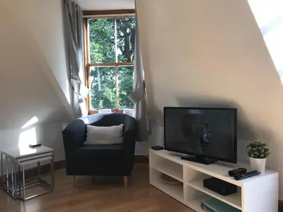 a living room with a television and a chair at STYLISH APARTMENT with PRIVATE ROOF TERRACE in Edinburgh