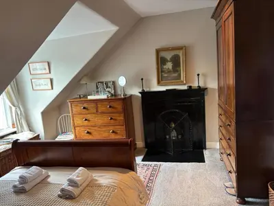 a bedroom with a bed and a dresser and a fireplace at Stunning 2-Bedroom Georgian Flat, City Centre in Edinburgh