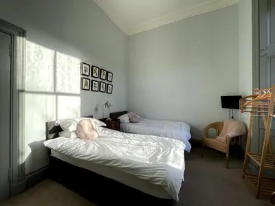 a bedroom with two beds and a chair and a window at 7 Crown Gardens Glasgow in Glasgow