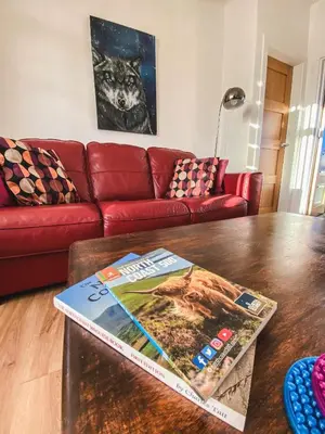 a living room with a red couch and a table at 20min to Edinburgh City Centre Scotland Gateway in Cowdenbeath