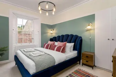 a blue bed in a room with a window at Charming and Cosy Getaway in Cambusbarron