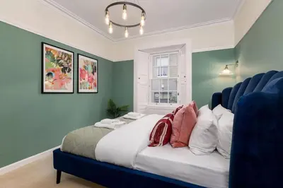 a bedroom with a bed with blue walls and a window at Charming and Cosy Getaway in Cambusbarron
