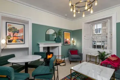 a living room with green chairs and a fireplace at Charming and Cosy Getaway in Cambusbarron