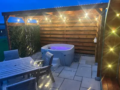 a bath tub sitting on a patio with a bench at Barnharrow Holiday Pods in Newton Stewart