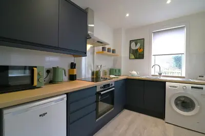 a kitchen with blue cabinets and a washing machine at Signature - St James House in Abbotsinch