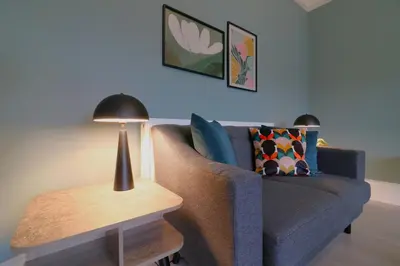 a living room with a couch and a table with a lamp at Signature - St James House in Abbotsinch