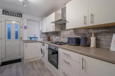 a kitchen with white cabinets and a stove top oven at Boswell House - Modern 3 Bed House East Kilbride Close to Motorway in East Kilbride