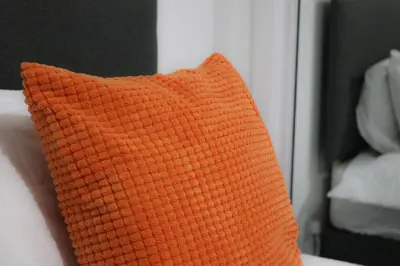 an orange pillow sitting on top of a bed at Sonas Apartment in Greenock