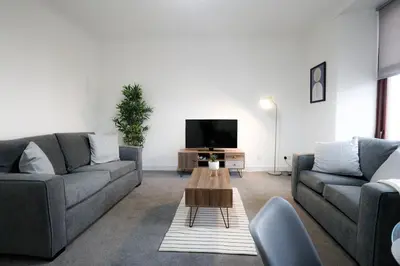 a living room with two couches and a tv at Sonas Apartment in Greenock