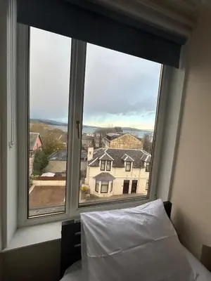 a bedroom window with a view of a house at The Bay View Apartment in Gourock