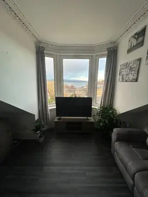 a living room with a flat screen tv and windows at The Bay View Apartment in Gourock