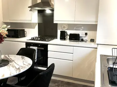 a kitchen with a stove and a table with chairs at Summerlee Gateaway in Coatbridge