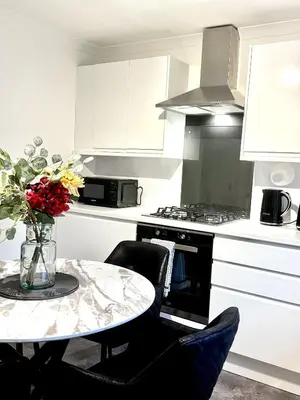 a kitchen with a table with a vase of flowers at Summerlee Gateaway in Coatbridge