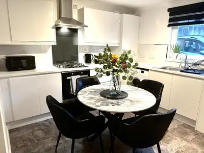 a kitchen with a table with a vase of flowers on it at Summerlee Gateaway in Coatbridge